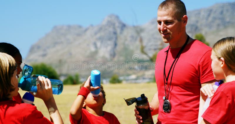 Trainer and kids drinking water in the boot camp stock footage