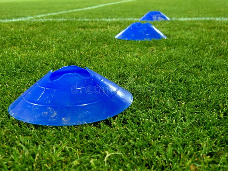 Bright Plastic Sports Cones on the Green Grass Outdoors To Train the