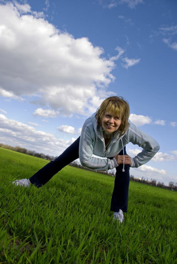 Usmievavá žena robiť fyzické cvičenia vonku.