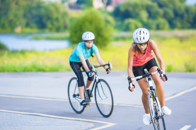Trainingszyklus der zwei weiblichen kaukasischen Sportlerinnen, die s reiten lizenzfreie stockbilder Trainingszyklus der zwei weiblichen kaukasischen Sportlerinnen, die s reiten lizenzfreie stockbilder