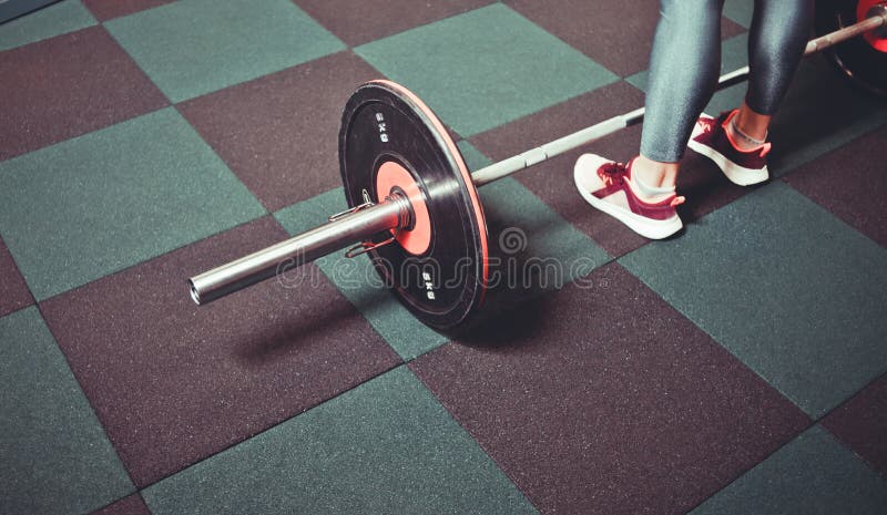 Trains de femme dans le gymnase avec un barbell image stock Trains de femme dans le gymnase avec un barbell image stock