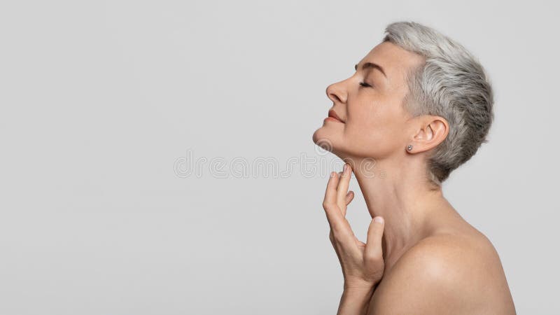 Traitement d'antiage. Belle femme entre deux âges touchant la peau douce sur le cou photographie stock libre de droits