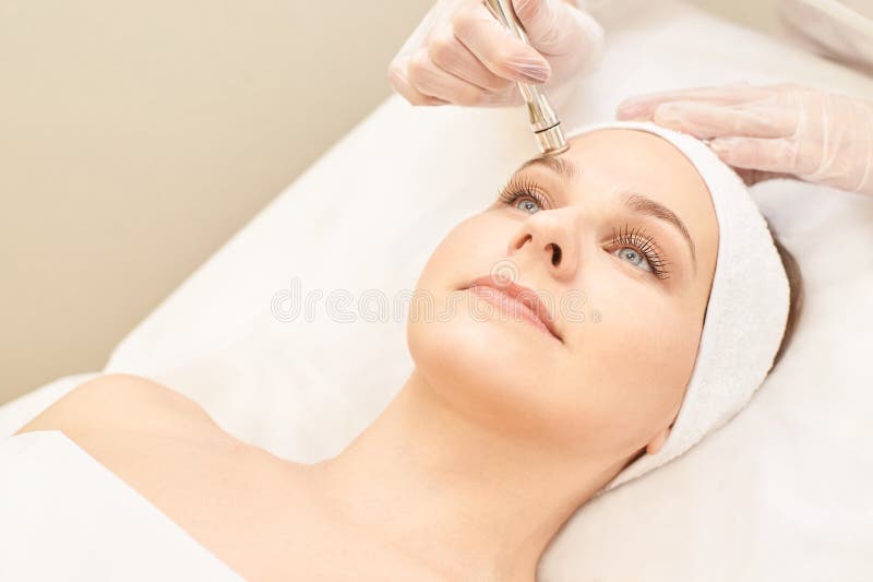 Traitement de visage de cosmétologie Jeune fille patiente Matériel cosmétique de salon Peau de diamant de dermatologie propre image stock Traitement de visage de cosmétologie Jeune fille patiente Matériel cosmétique de salon Peau de diamant de dermatologie propre image stock