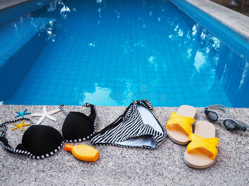 Traje y accesorios de nataci?n de la mujer en el borde de la piscina foto de archivo libre de regalías Traje y accesorios de nataci?n de la mujer en el borde de la piscina foto de archivo libre de regalías