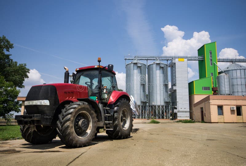 Tractor parked in front of grain silos. Tractor parked in front of grain silos