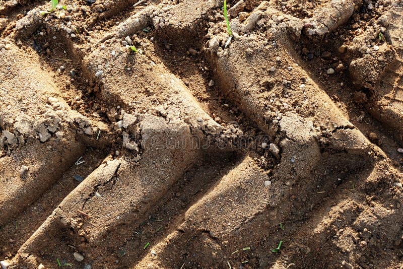 Beautiful tractor sand tracks closeup texture, background. Agricultural natural ground backdrop. Background for farmers, agriculture workers design. Beautiful tractor sand tracks closeup texture, background. Agricultural natural ground backdrop. Background for farmers, agriculture workers design.