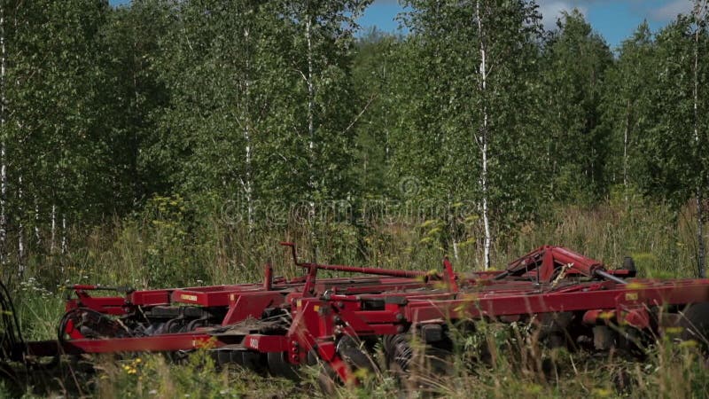 Traktoren med chaufförkonturn i den hitched kabinen fungerar på våren som sparas nära en björkskog