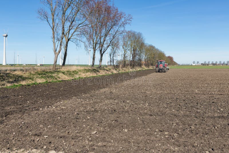 Traktorpflug am bloßen Holländerfeld im frühen Frühjahr lizenzfreies stockbild Traktorpflug am bloßen Holländerfeld im frühen Frühjahr lizenzfreies stockbild