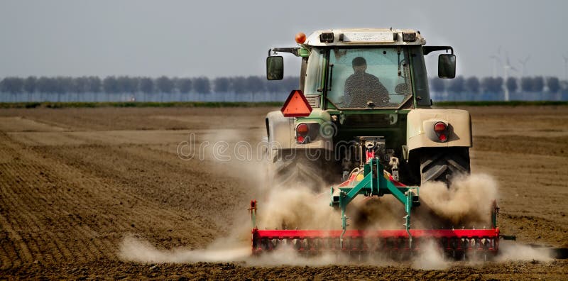 Tractor working on farmland kicking up dust. Tractor working on farmland kicking up dust