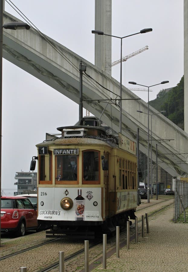 Tram di vintage che passa sotto il ponte di Arribida a Porto fotografie stock libere da diritti