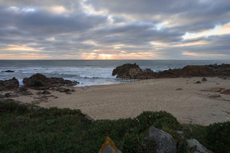Tramonto sotto le nuvole scure su una spiaggia rocciosa fotografia stock libera da diritti Tramonto sotto le nuvole scure su una spiaggia rocciosa fotografia stock libera da diritti