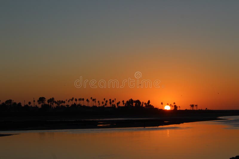 Sun is sinking below the skyline at the Ocean Beach, San Diego, California, USA. The sky is shinning golden light and so beautiful at this moment. The water is reflecting the golden sky and the sea birds are resting peacefully. Sun is sinking below the skyline at the Ocean Beach, San Diego, California, USA. The sky is shinning golden light and so beautiful at this moment. The water is reflecting the golden sky and the sea birds are resting peacefully.