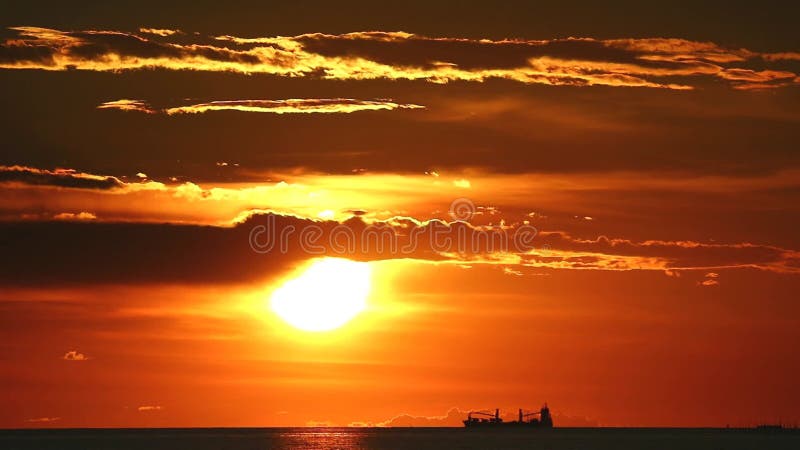 Tramonto sulla nuvola nera in mare e su una nave da carico di silhouette in estate