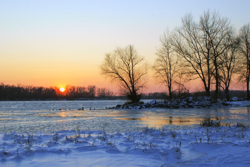 Tramonto sulla riva di grande fiume nell'inverno fotografia stock Tramonto sulla riva di grande fiume nell'inverno fotografia stock