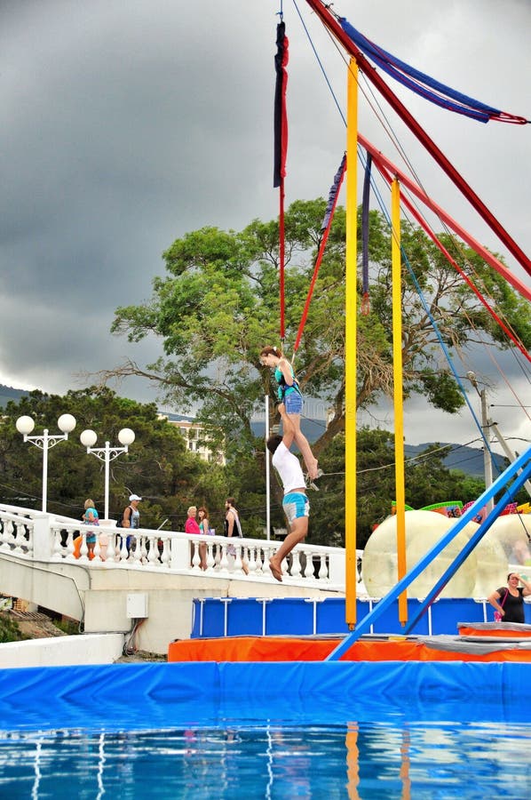 Salto Del Amortiguador Auxiliar De Los Niños En Los Trampolines En El
