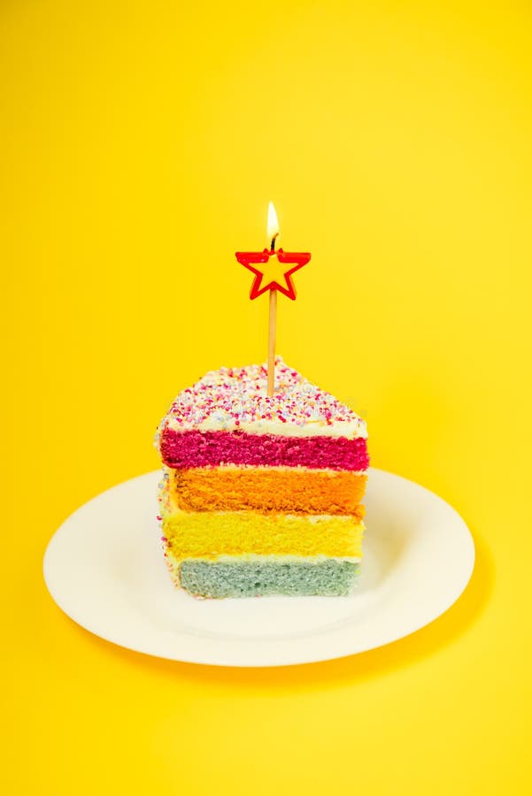 Tranche De Gateau D Arc En Ciel Avec La Bougie Birning Sous Forme D Etoile Du Plat Rond Blanc D Isolement Sur Le Fond Jaune Lumin Photo Stock Image Du Dessert Flamme