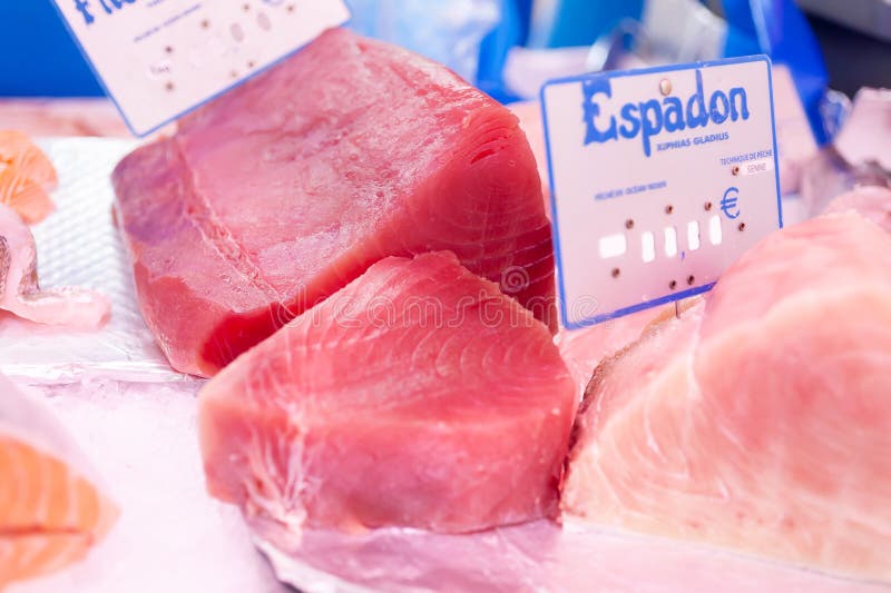 Fresh blocks of fish on display,tuna and swordfish,red and pink with blue tags on the fisherman's stand. Fresh blocks of fish on display,tuna and swordfish,red and pink with blue tags on the fisherman's stand.