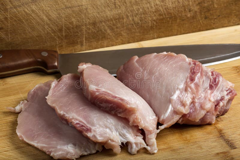 Tranches de viande fraîche d'aloyau de por avec un couteau de cuisine image stock Tranches de viande fraîche d'aloyau de por avec un couteau de cuisine image stock