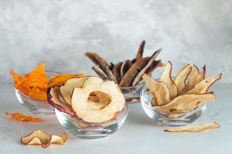 Tranches sèches de fruits de pêche, pomme, potiron, banane dans des bols en verre image stock Tranches sèches de fruits de pêche, pomme, potiron, banane dans des bols en verre image stock