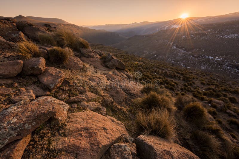 A tranquil golden snow-covered rocky mountain landscape taken at sunset