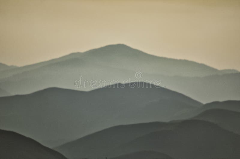 Misty Layers of Rolling Hills Under a Soft Golden Sky