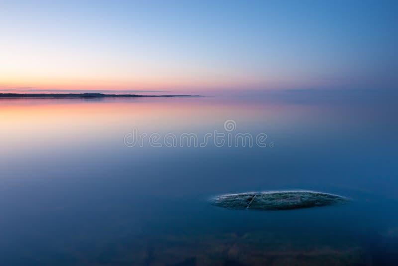Tranquil minimalist landscape with rock in calm water