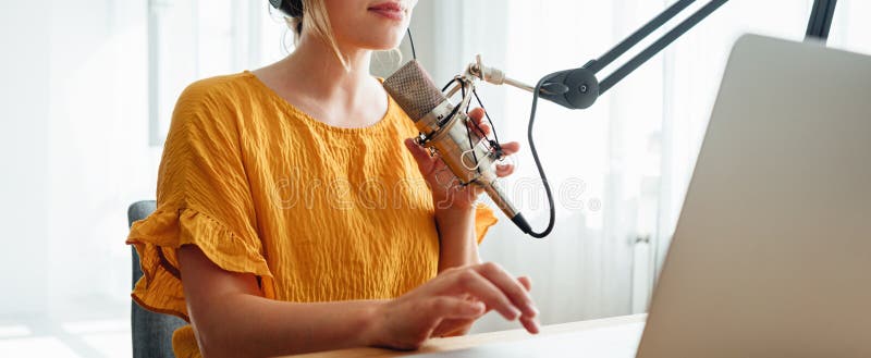 Transmisje strumieniowe dla kobiet w podkaście audio za pomocą mikrofonu i laptopa w jego małym studio. obraz szeroki zdjęcie stock