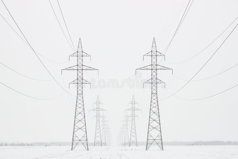 Transmission Towers To Horizon in Winter, Horizontal Crop. Two lines of transmission towers marching toward the horizon in a white winter scene, horizontal crop royalty free stock images Transmission Towers To Horizon in Winter, Horizontal Crop. Two lines of transmission towers marching toward the horizon in a white winter scene, horizontal crop royalty free stock images