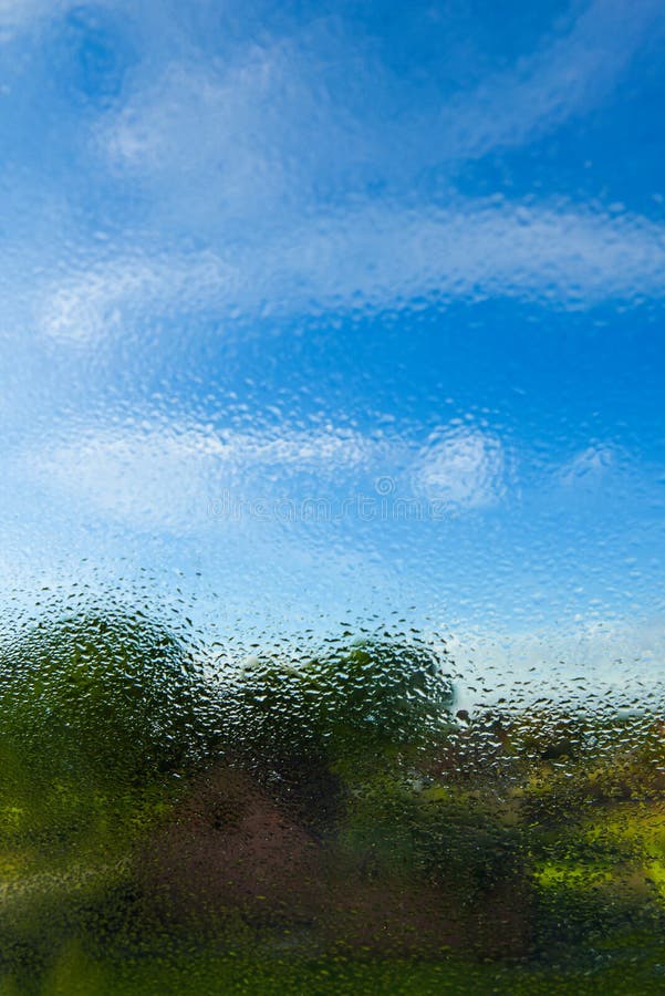 Transparante schone regendruppels op het glas tegen de achtergrond van heldere blauwe hemel met wolken Grafisch middel, prentbrie royalty-vrije stock afbeeldingen Transparante schone regendruppels op het glas tegen de achtergrond van heldere blauwe hemel met wolken Grafisch middel, prentbrie royalty-vrije stock afbeeldingen