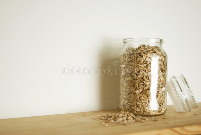 Transparent glass with oat meals in glass jar, isolated isolated on wooden table. Healthy breakfast ingredient. royalty free stock photography Transparent glass with oat meals in glass jar, isolated isolated on wooden table. Healthy breakfast ingredient. royalty free stock photography