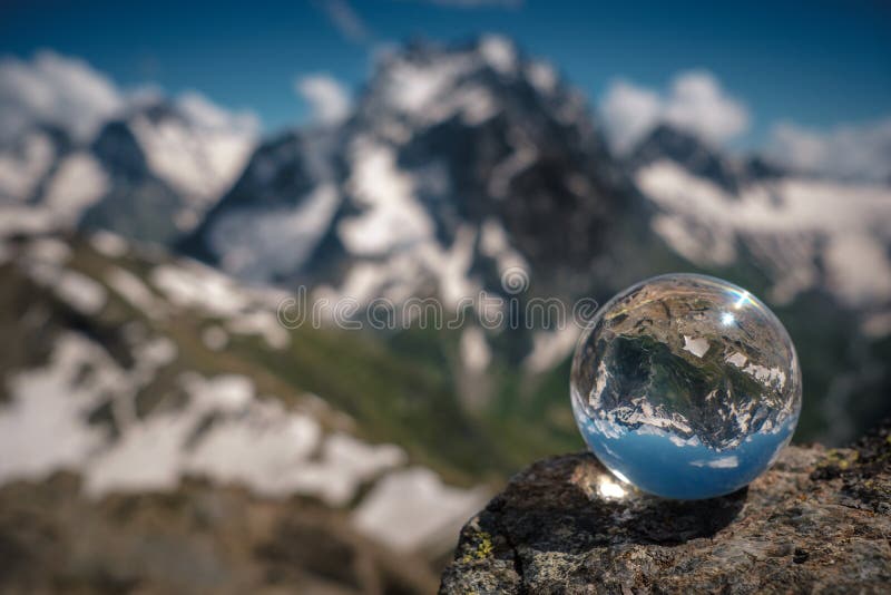 Transparent glass sphere and snow-capped peaks in the background