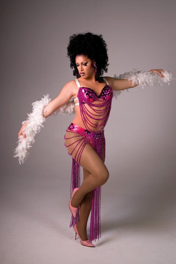 Full length shot of a beautiful Drag queen wearing a pink beaded showgirl costume, with a white feather boa wrapped around both arms. Full length shot of a beautiful Drag queen wearing a pink beaded showgirl costume, with a white feather boa wrapped around both arms.