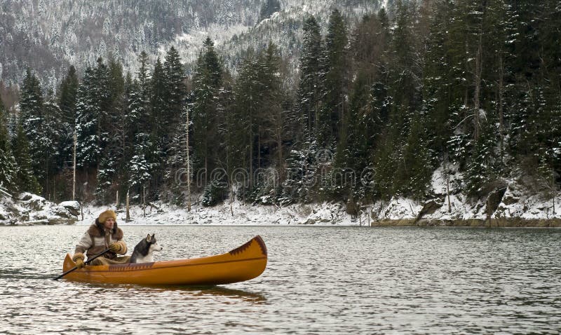 L'uomo e il suo cane Husky in canoa su un lago durante la stagione invernale, in Transilvania, Romania.