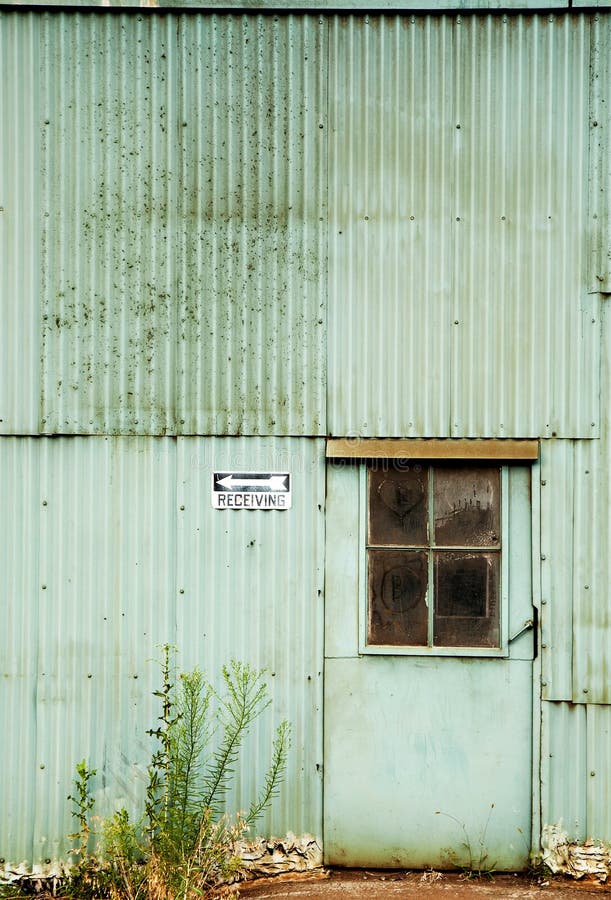 Abandoned Factory with Green Corrugated Metal Walls, Weeds, Door and Receiving Sign. Abandoned Factory with Green Corrugated Metal Walls, Weeds, Door and Receiving Sign