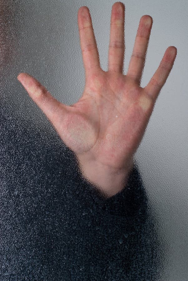 Closeup of a hand pressed against some frosted glass.