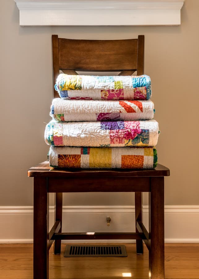 Quilts Stacked on Wooden Chair against neutral wall. Quilts Stacked on Wooden Chair against neutral wall