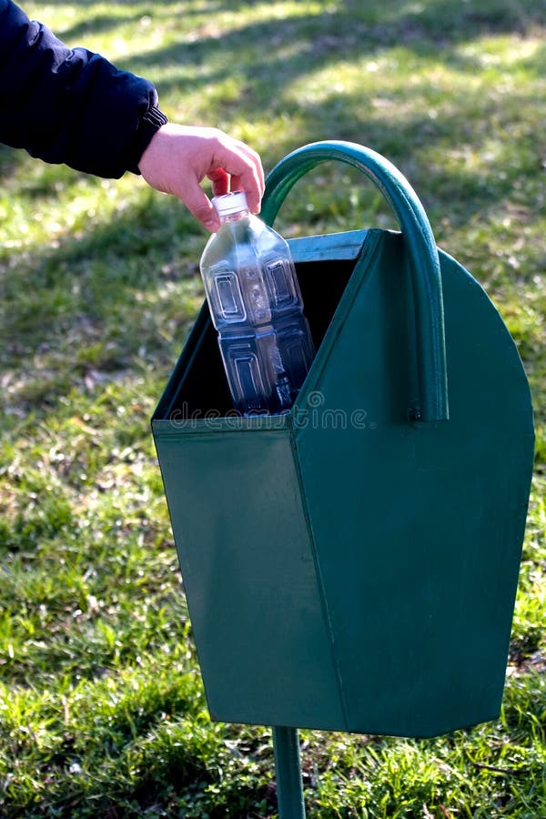 Male hand throwing an empty plastic bottle in a trash can