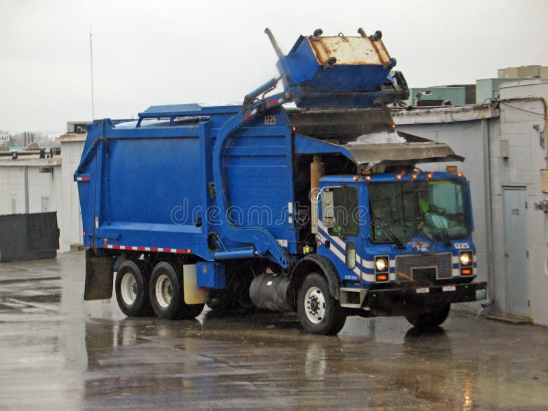 Azul basura camión coleccionando cesta en la lluvia.