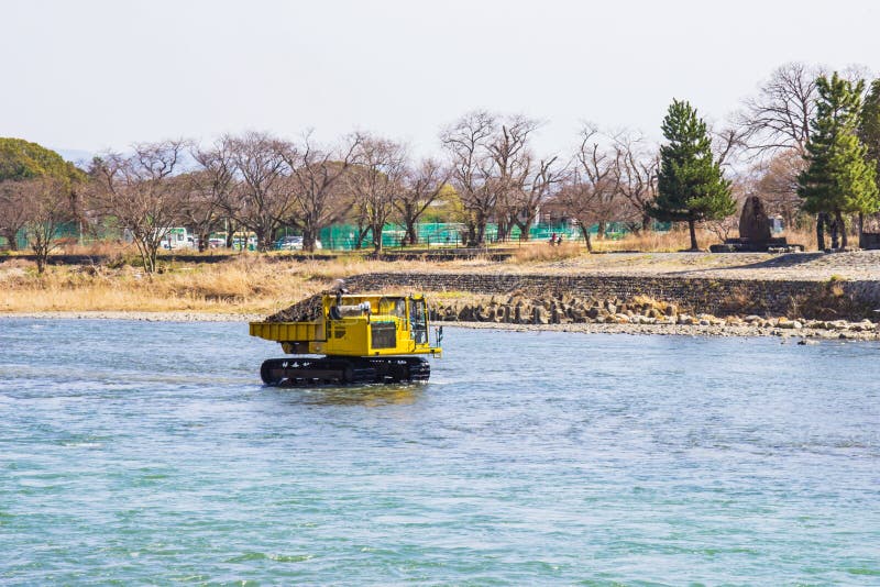 Trasporti e pietra di dragaggio in fiume Katsura per fare lo scorrimento dell'acqua fotografia stock Trasporti e pietra di dragaggio in fiume Katsura per fare lo scorrimento dell'acqua fotografia stock