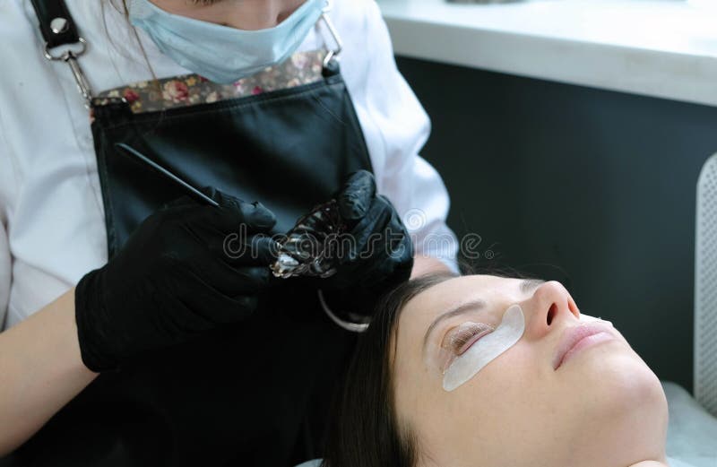 Tratamento da beleza O Cosmetologist põe a pintura preta sobre os chicotes Botox e pestanas de estratificação fotografia de stock royalty free Tratamento da beleza O Cosmetologist põe a pintura preta sobre os chicotes Botox e pestanas de estratificação fotografia de stock royalty free