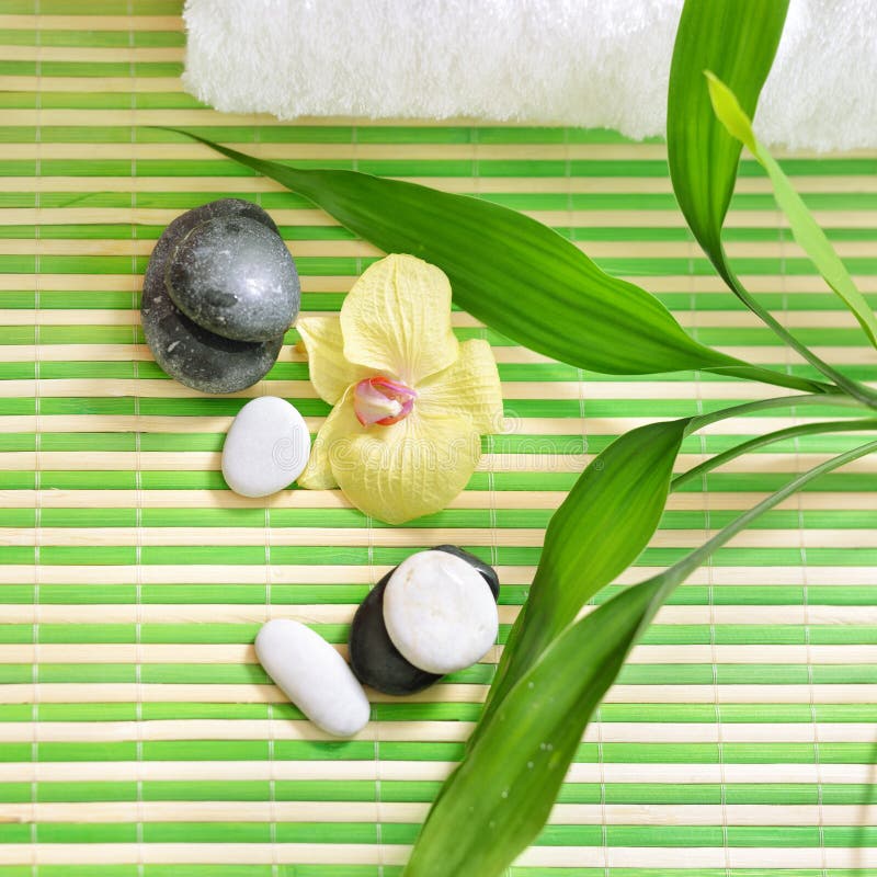 Tratamiento del balneario con las piedras, la flor de la orquídea y el bambú verde imagen de archivo libre de regalías Tratamiento del balneario con las piedras, la flor de la orquídea y el bambú verde imagen de archivo libre de regalías