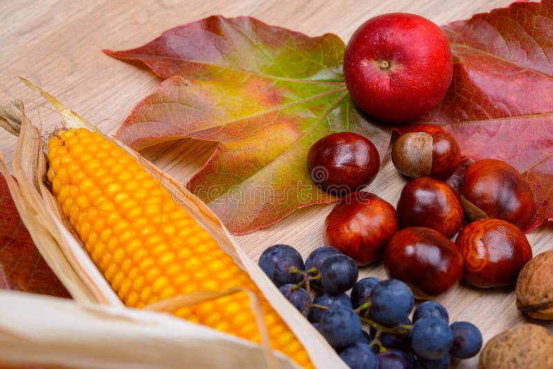 Trauben, Blätter, Apfel, Maiskolben, Kastanie und Walnuss auf hölzernem GR stockfoto