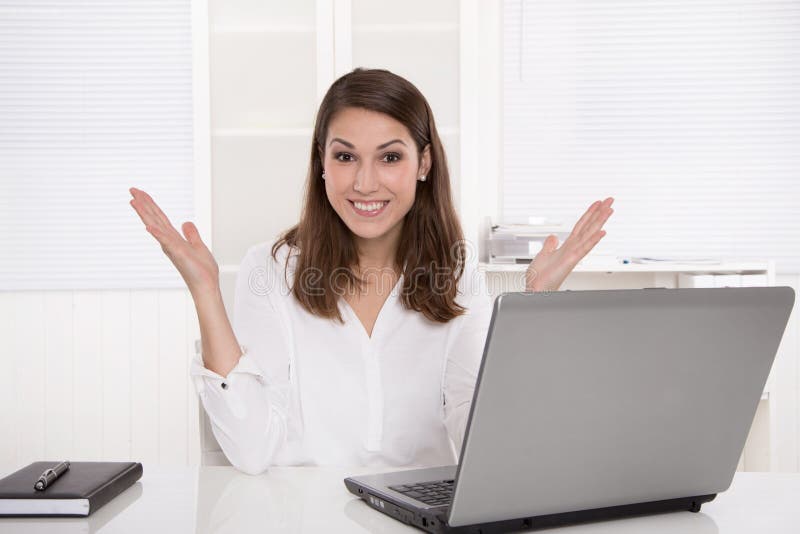 Traumjob: erfolgreiche lächelnde Geschäftsfrau, die am Schreibtisch mit sitzt lizenzfreie stockfotografie