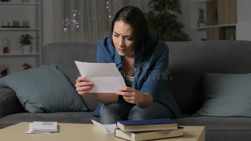 Traurige Frau, die einen Brief in der Nacht lesend sich beschwert