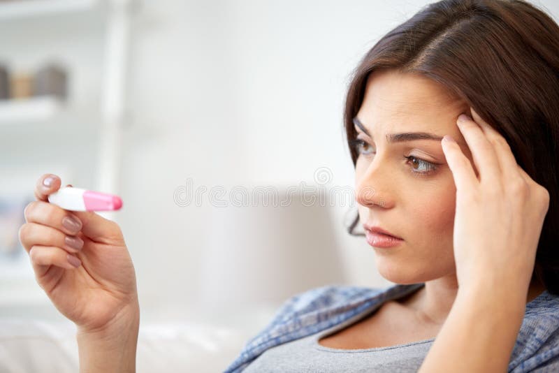 Traurige Frau, die zu Hause Schwangerschaftstest schaut stockfoto Traurige Frau, die zu Hause Schwangerschaftstest schaut stockfoto