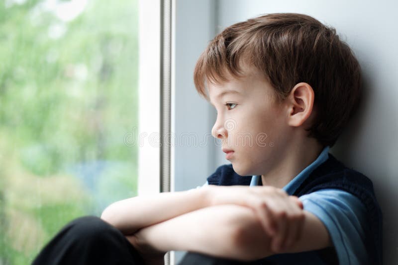 Trauriger Junge, der auf Fenster sitzt lizenzfreies stockbild Trauriger Junge, der auf Fenster sitzt lizenzfreies stockbild