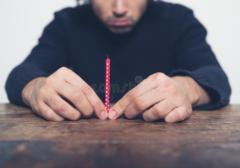 Trauriger junger Mann mit kleiner Kerze stockbild Trauriger junger Mann mit kleiner Kerze stockbild