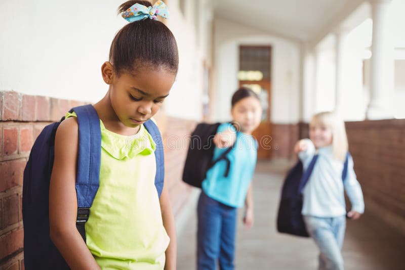 Trauriger Schüler, der von den Mitschülern am Korridor eingeschüchtert wird lizenzfreie stockfotografie Trauriger Schüler, der von den Mitschülern am Korridor eingeschüchtert wird lizenzfreie stockfotografie