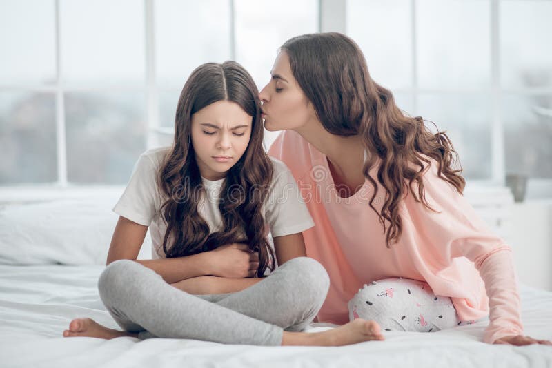 Trauriges Mädchen mit den sinkenden Augenlidern und küssen Mutter lizenzfreie stockfotografie