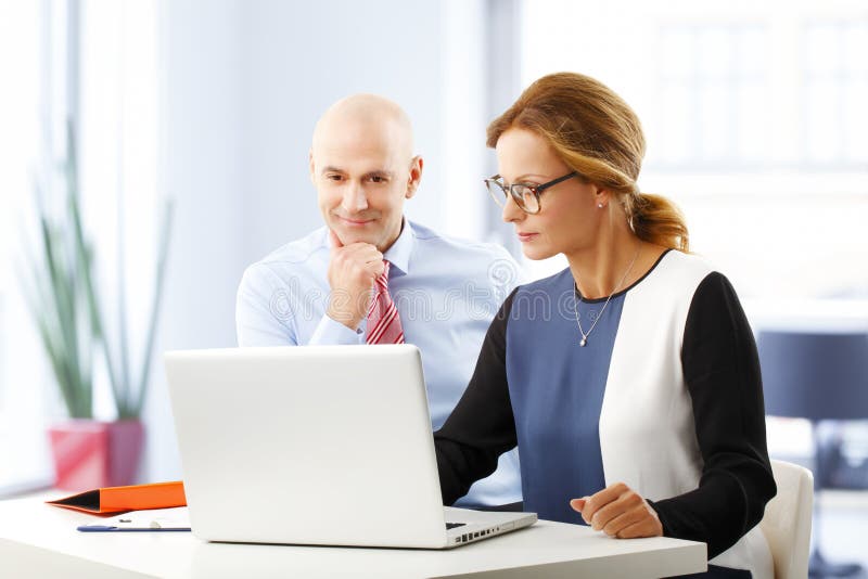 Portrait of efficiency business people analyzing datas on laptop, while sitting at desk in bank. Portrait of efficiency business people analyzing datas on laptop, while sitting at desk in bank.